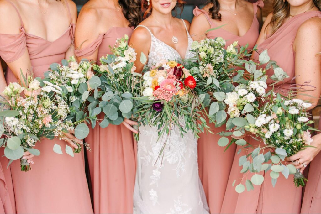 A bride and bridesmaids hold lush bouquets with earthy tones, capturing the charm of a wedding weekend in Santa Fe.