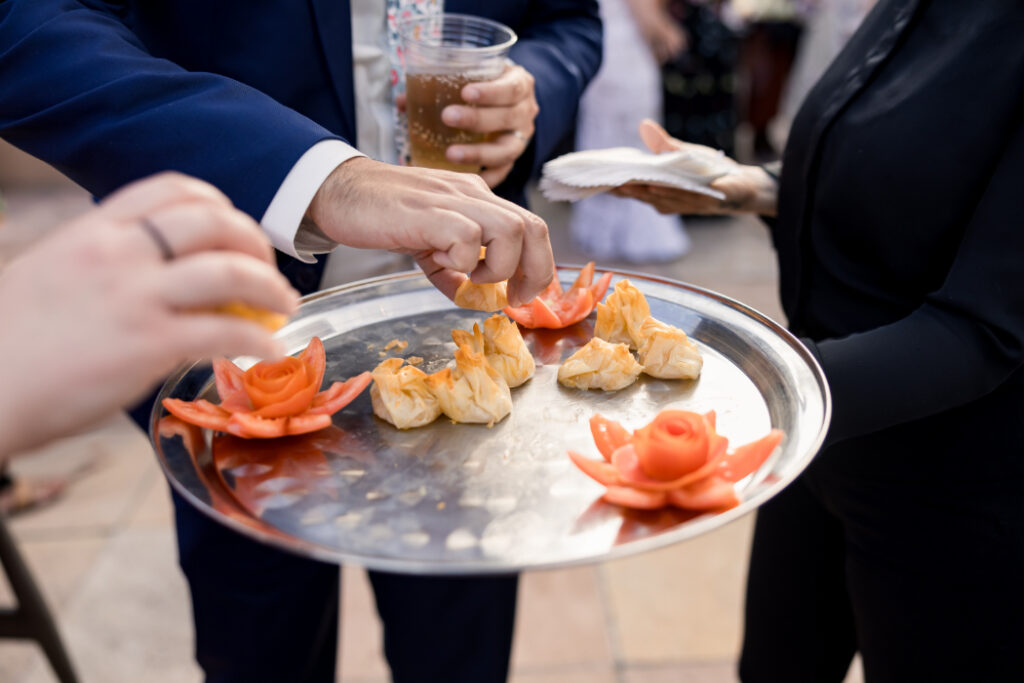 Guests pick up appetizers from a tray featuring golden pastries and carved vegetable garnishes | catering santa fe.