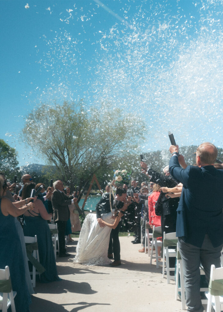 Bride and groom exit ceremony with guests popping confetti canons, one of their favorite unconventional wedding ideas.