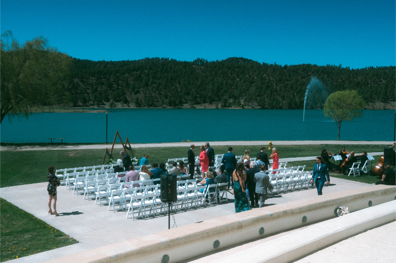 Guests arrive and take seats for a Ruidoso wedding ceremony with lake and mountain views.
