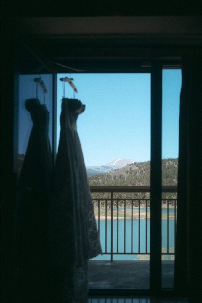 Wedding dress hangs from terrace overlooking lake backdrop below.