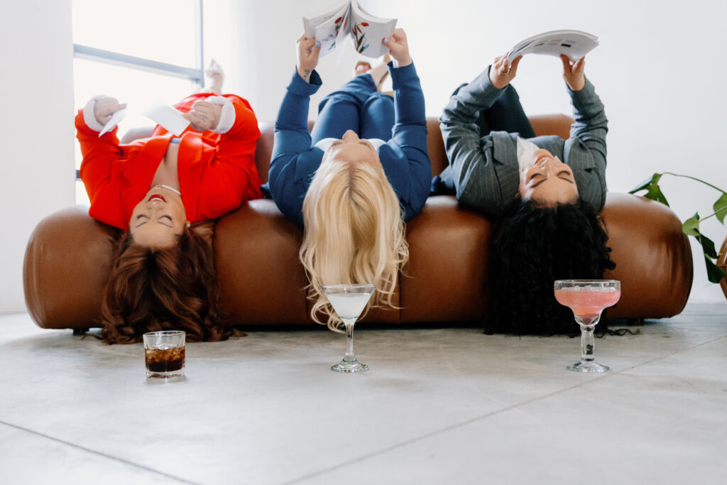 Verdeaux & Co. team pose for a photo as they lay on a couch reading magazines, their signature drinks sitting in front of each of them.