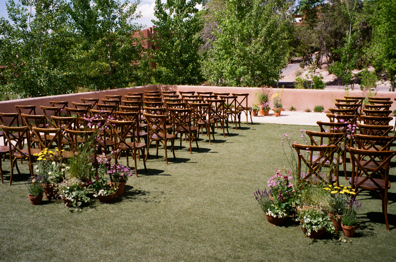 Ceremony at Bishop's Lodge, set with garden wedding aesthetic florals in terracotta pots at the base of the aisle.