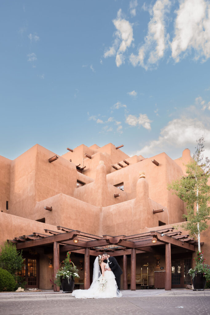 Groom dips bride for a kiss in from of the Inn and Spa at Loretto.