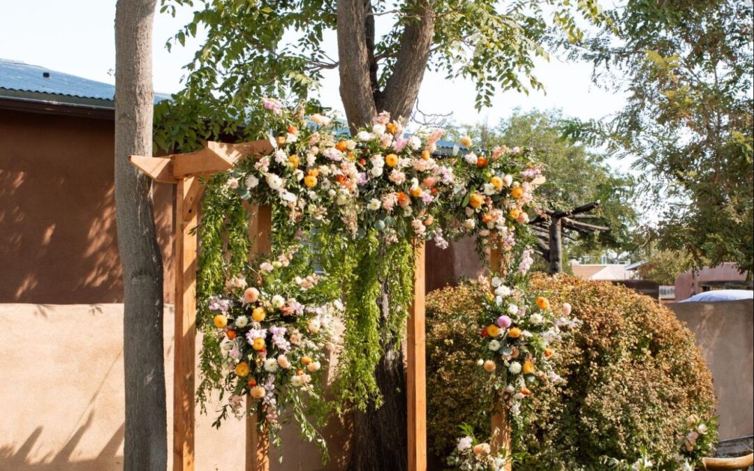 Outdoor ceremony with wooden arbor, cascading florals, and rustic chairs embodying nature-inspired 2025 wedding trends.