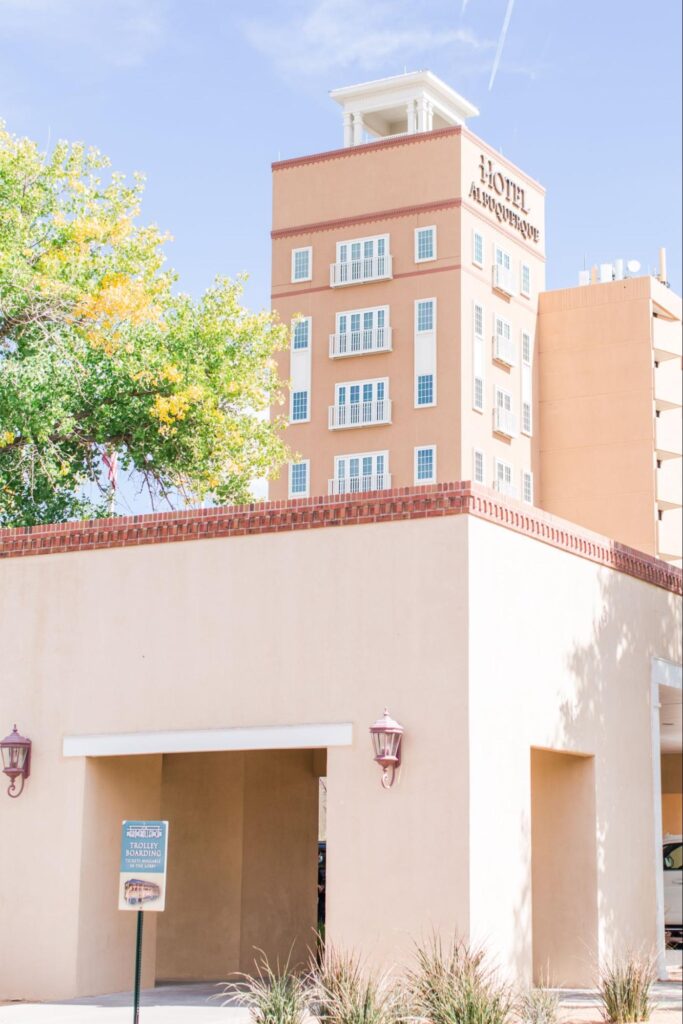 Hotel Albuquerque building with adobe-style design and trees nearby.