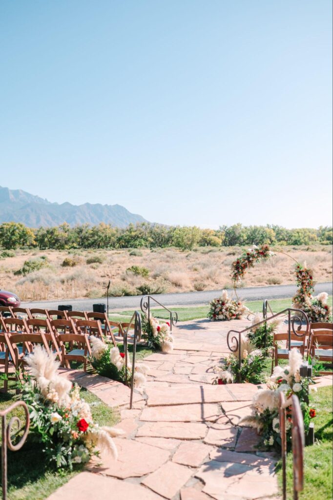 Outdoor ceremony with mountain views, a floral arch, and rustic stone aisle surrounded by greenery.