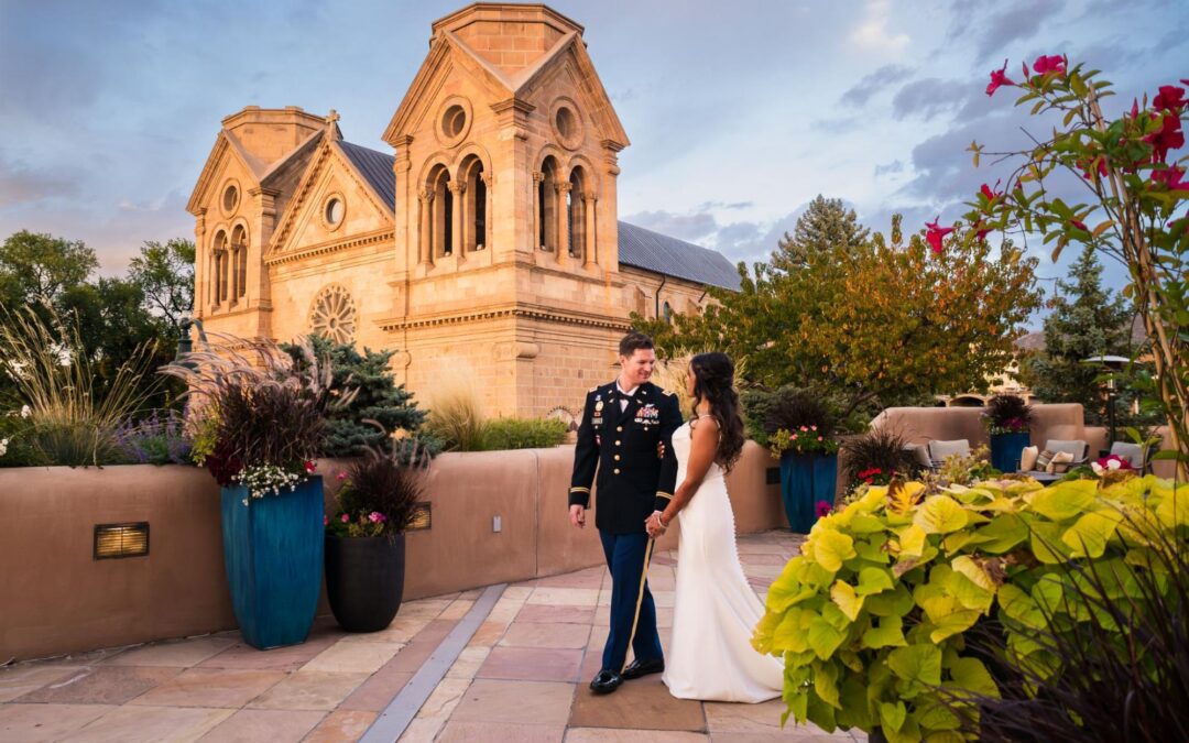 A stunning couple poses outside a historic Santa Fe church during their wedding weekend in Santa Fe, surrounded by vibrant flowers.