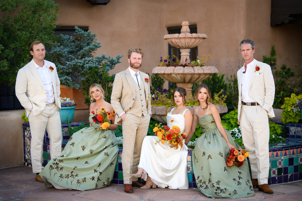 A wedding party poses in front of a Spanish-style courtyard fountain at La Fonda on the Plaza.