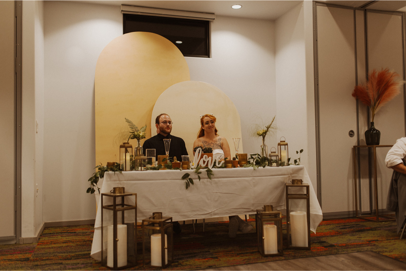Bride and groom sit at sweetheart table during fall wedding reception in New Mexico.