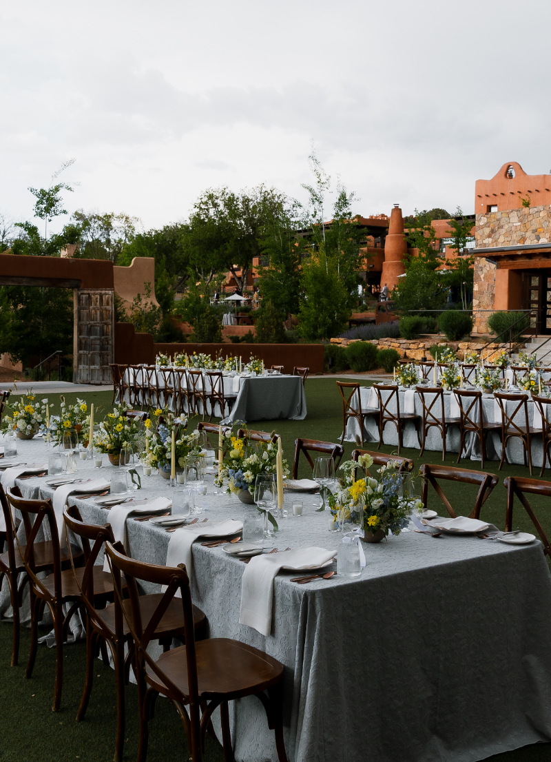 Table setting for reception at Bishop's Lodge in Santa Fe with light blue tablecloth, place setting for guests, and low floral arrangements.