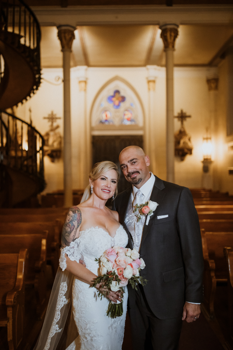 Bride and groom pose together in Loretto Chapel.