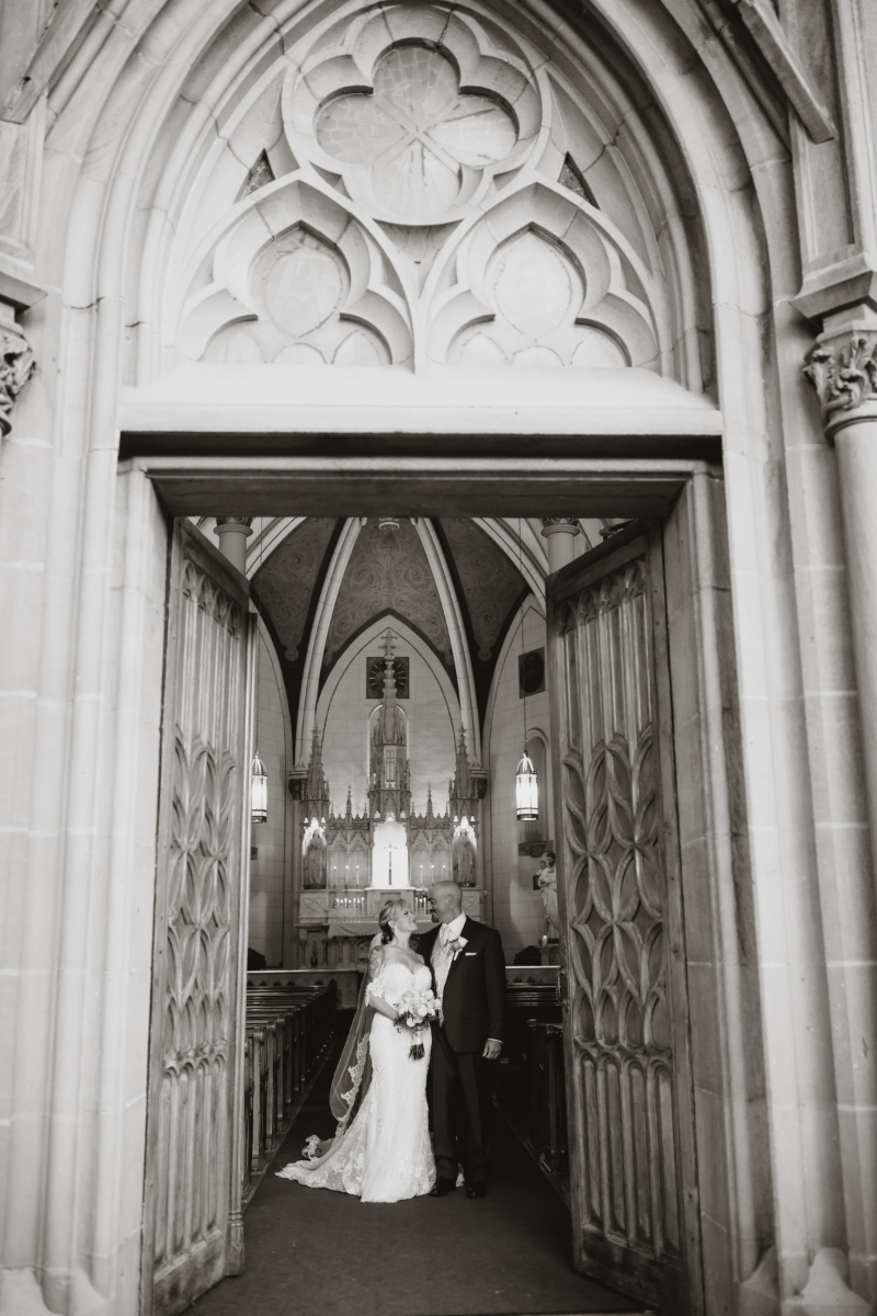 Bride and groom pose together in Loretto Chapel.