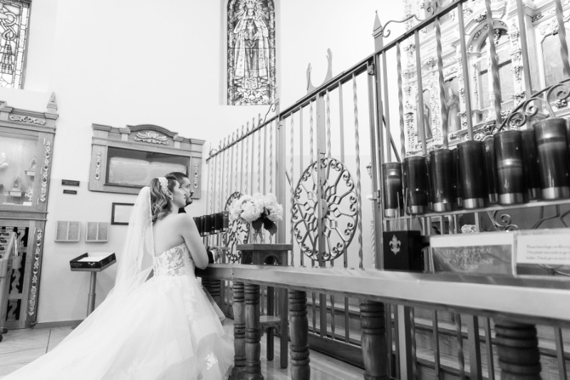 Bride and groom kneeling during service at their wedding in Loretto Chapel.